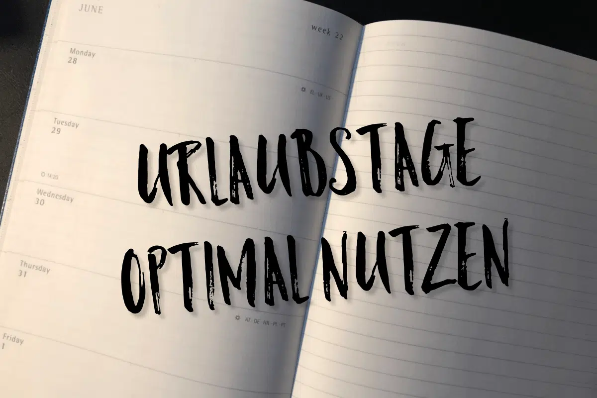 Ein aufgeschlagener Terminkalender zeigt Termine Ende Juni. Auf den Seiten steht in fetter schwarzer Handschrift: „Urlaubstage optimal nutzen“. Das Licht ist warm, und man sieht die Ecke eines Tisches – eine perfekte Kulisse, um den nächsten Urlaub zu planen.