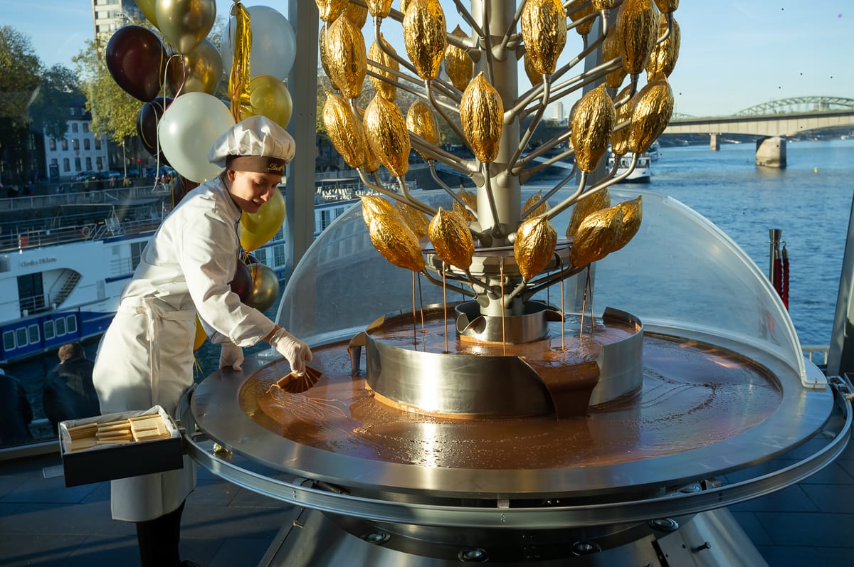 Lindt-Mitarbeiter bereiten die Waffeln mit Schokolade aus dem Brunnen für Besucher vor