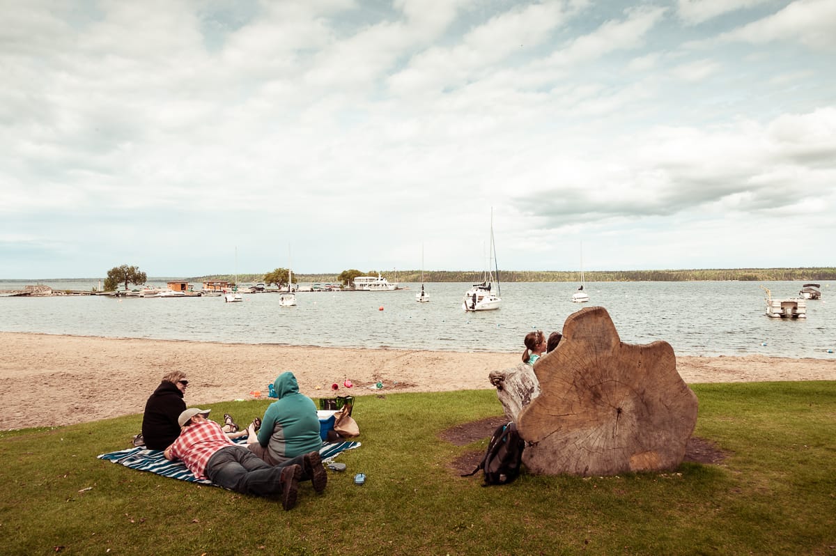 Am Ufer des Clear Lakes in Wasagaming sitzt eine Familie auf einer Picknickdecke.