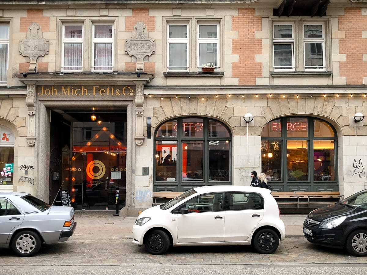 Außenansicht des Ladens in der Schanzenstraße, Hamburg von der gegenüberliegenden Seite mit parkenden Autos vor dem Laden.