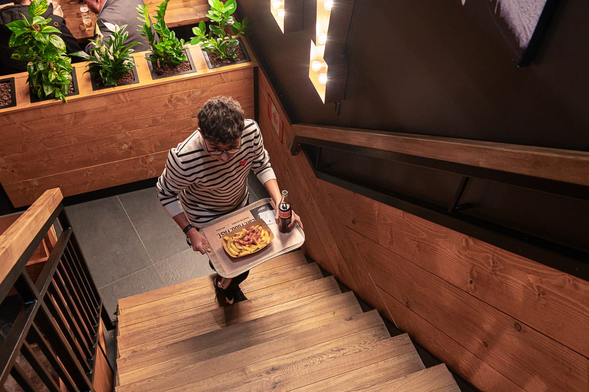 Frittenwerk Oberhausen - ein Kunde geht mit einem Tablett und Poutine die Treppe hinauf.