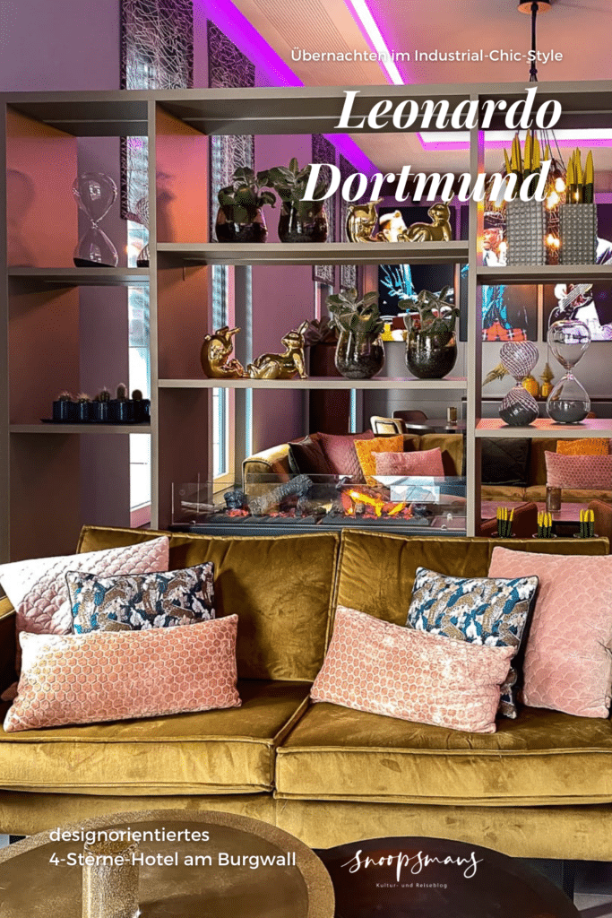 Pinterest-Grafik passend zum Artikel mit Bild aus dem Restaurant mit gemütlicher Couch mit vielen Kissen in der offenen Lobby, ein aufbereiteter Pin mit Text-Overlay.