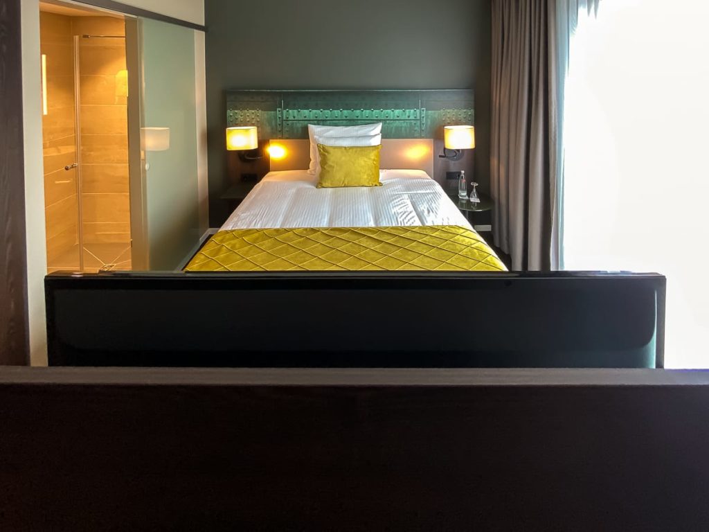 Blick über den drehbaren Flatscreen auf das Bett im Deluxe Zimmer.
