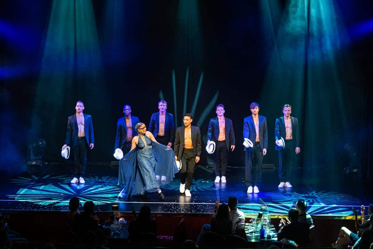 Rosemie und die Wild Boys auf der Bühne am Ende der Show. Die Herren im Sakko, Oberkörper darunter frei, Hut in der Hand. Rosemie in einem blauen, langen Abendkleid.