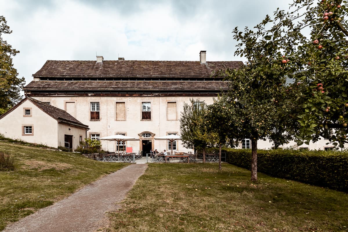 Rückseite des Klosters mit Außenterrasse des Klosterwirtshauses mit einer Reihe von Obstbäumen rechts am Weg zur Terrasse.