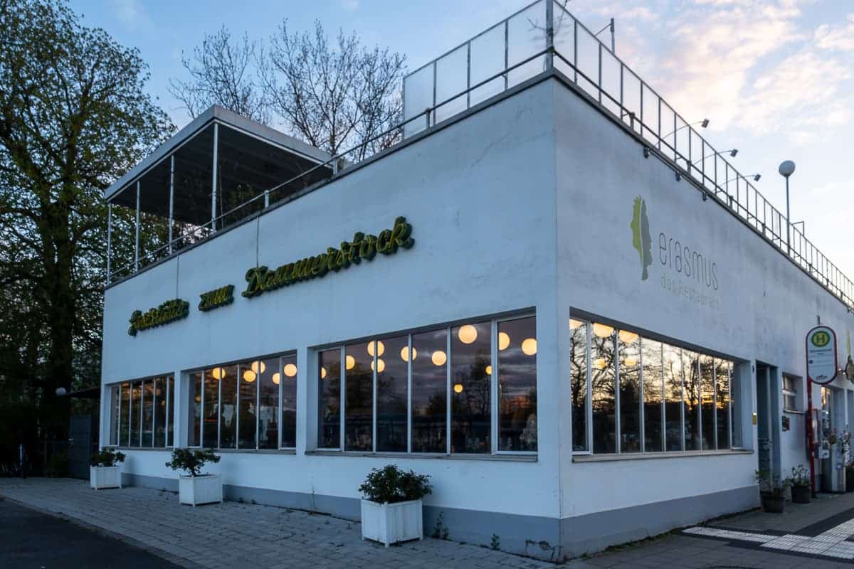 Gaststätte zum Dammerstock - weißes Gebäude der "Neuen Sachlichkeit", große Fenster, kugelförmige Lampen leuchten im Inneren, Karlsruhe-Dammerstock, mir Restaurant erasmus.