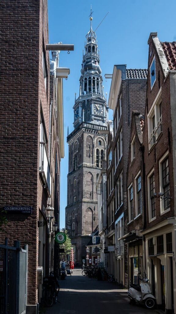 Kirchturm der Oude Kerk Amsterdam durch eine schmale Gasse fotografiert.