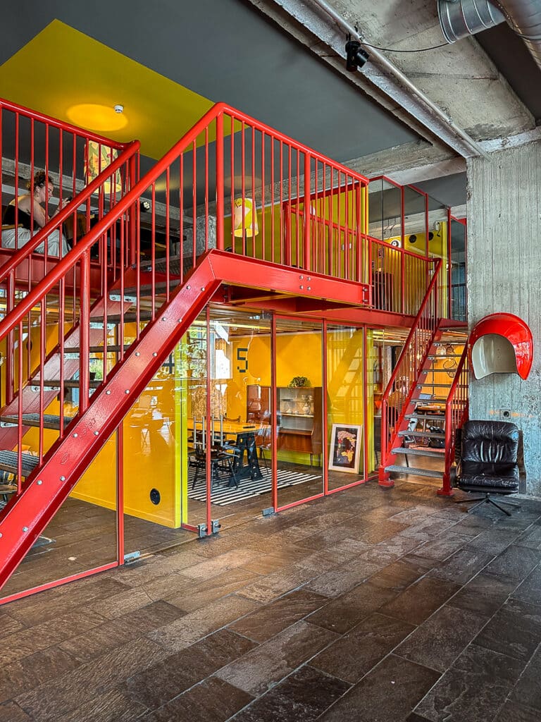 Meetingräume im Volkshotel Amsterdam und Coworking - zwei Etagen mit abgeschlossenen kleinen Räumen für Meetings und zum Telefonieren, Metalltreppen führen nach oben.