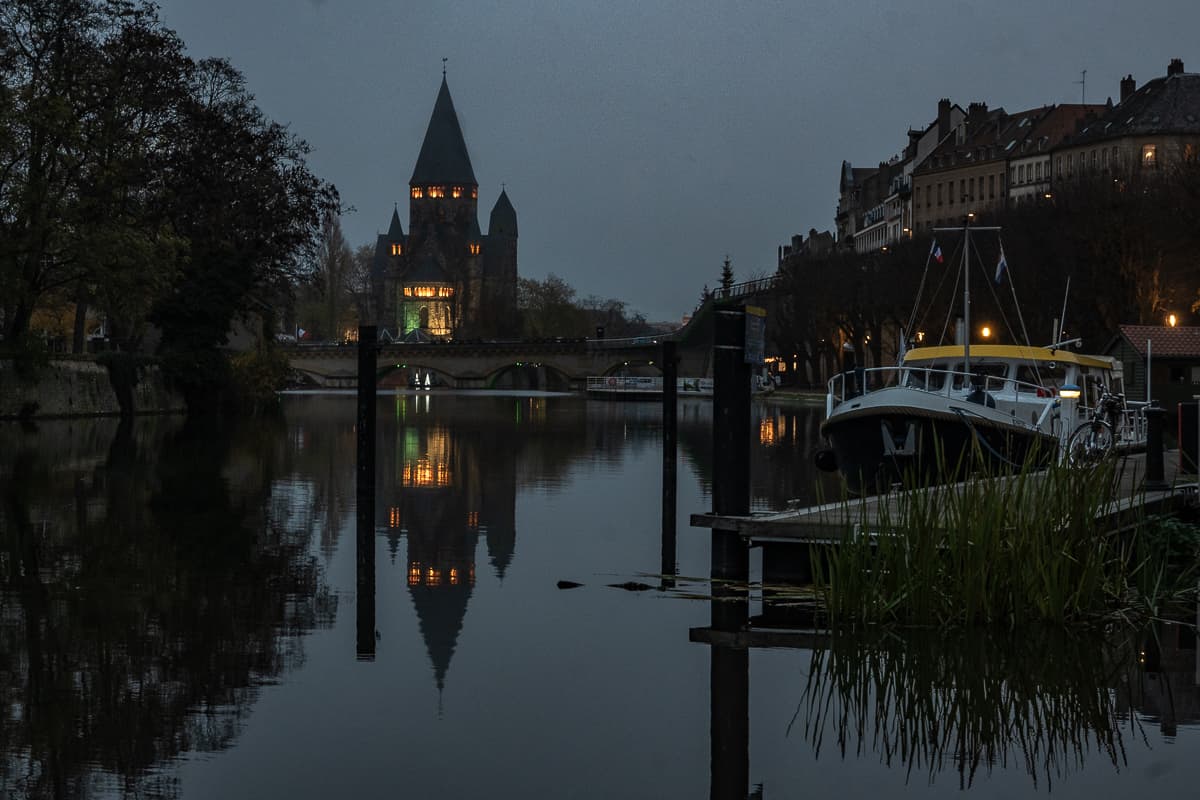 Dämmerung an der Mosel, Kirche Temple Neuf im Hintergrund, vorne rechts liegt ein Boot, Spiegelung im Wasser.