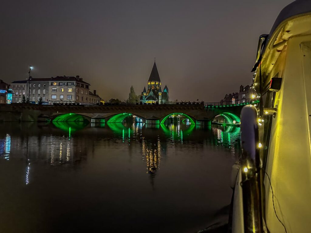 Beleuchtete Brücke Moyen Pont mit Temple Neuf im Hintergrund, vom Boot aus, Spiegelungen in der ruhigen Mosel.