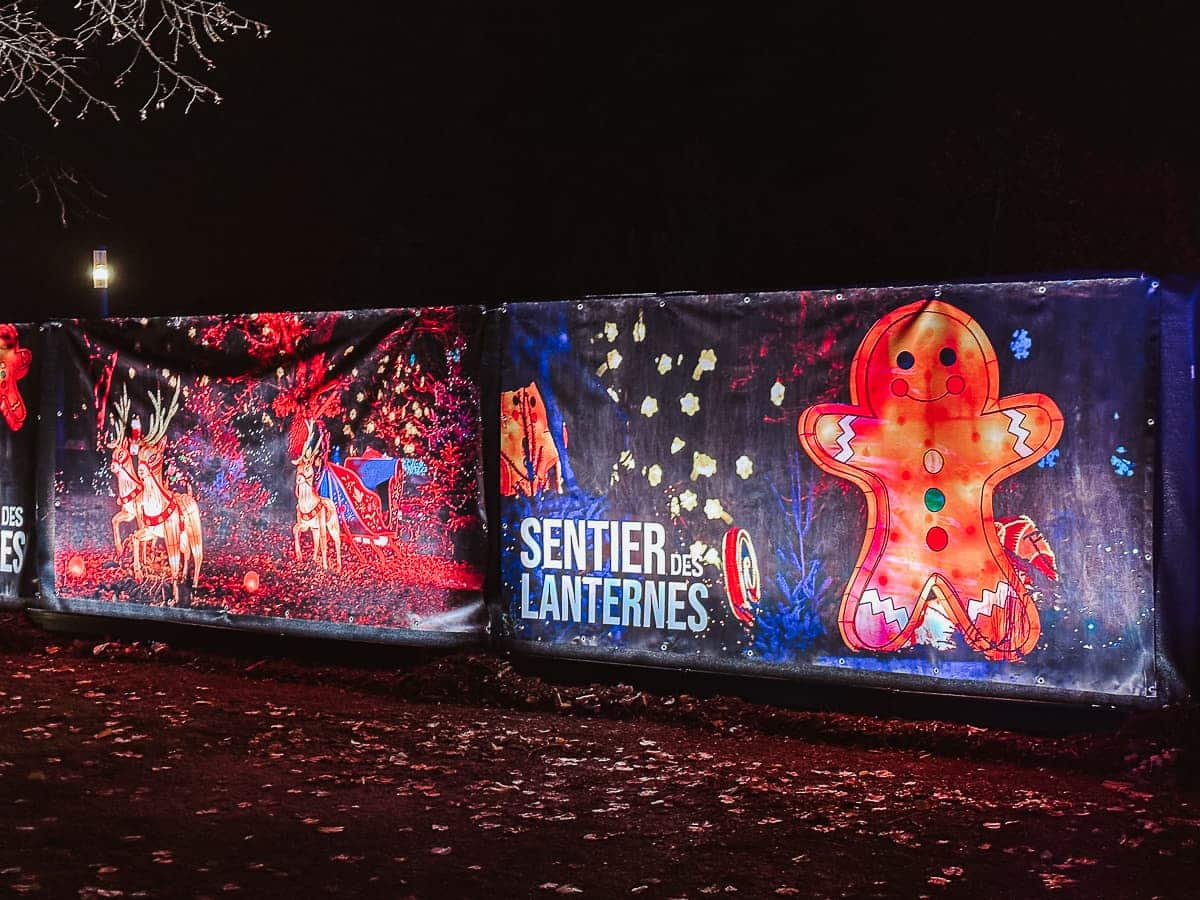 Eingang zum Laternenpfad "La Sentier des Lanternes" während des Weihnachtsmarkt Metz - Plane mit Lebkuchenmann und weiteren weihnachtlichen Motiven, Schriftzug Sentier des Lanternes.