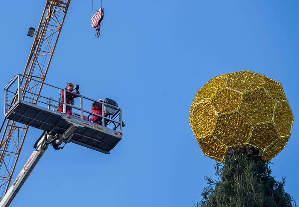 Richtfest. Aufgesetzte goldene Kugel, fußballförmig, auf der Baumspitze des Weihnachtsbaums in Dortmund, daneben Kran mit Bauarbeitern, die Spitze aufsetzten. Foto: Klaus Hartmann für nordstadtblogger.de mit freundlicher Genehmigung.