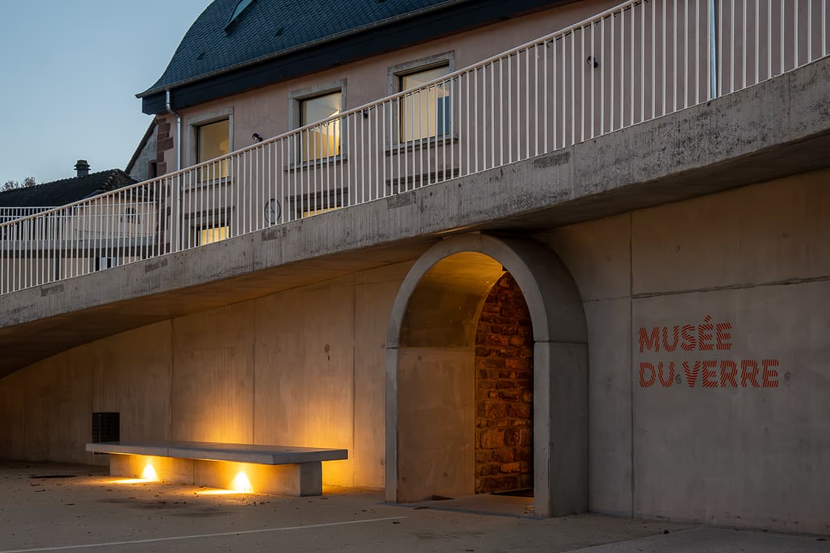 Eingang zum Glasmuseum in Meisenthal in der Dämerung mit Beleuchtung am Eingang und in den Fenstern.