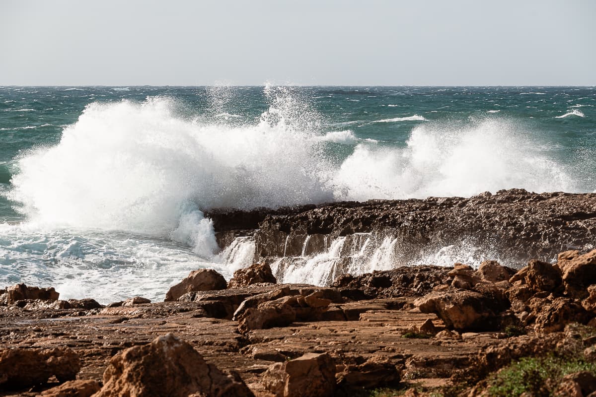 Hochtürmendes Wasser an der schroffen Küste von Cap de ses Salines auf Mallorca, hohes auftürmendes und auch vom Felsen fliesendes Wasser.
