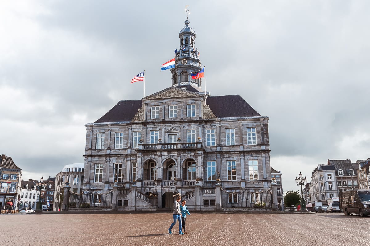 Freistehendes Rathaus auf dem Marktplatz. Ein Pärchen läuft mittig von links nach rechts vor dem Rathaus über den Platz.