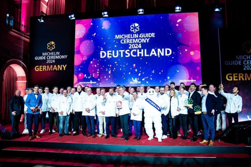 Gruppenbild mit allen 2024 im Michelin Guide ausgezeichneten Köch:innen sowie dem Michelin-Männchen.