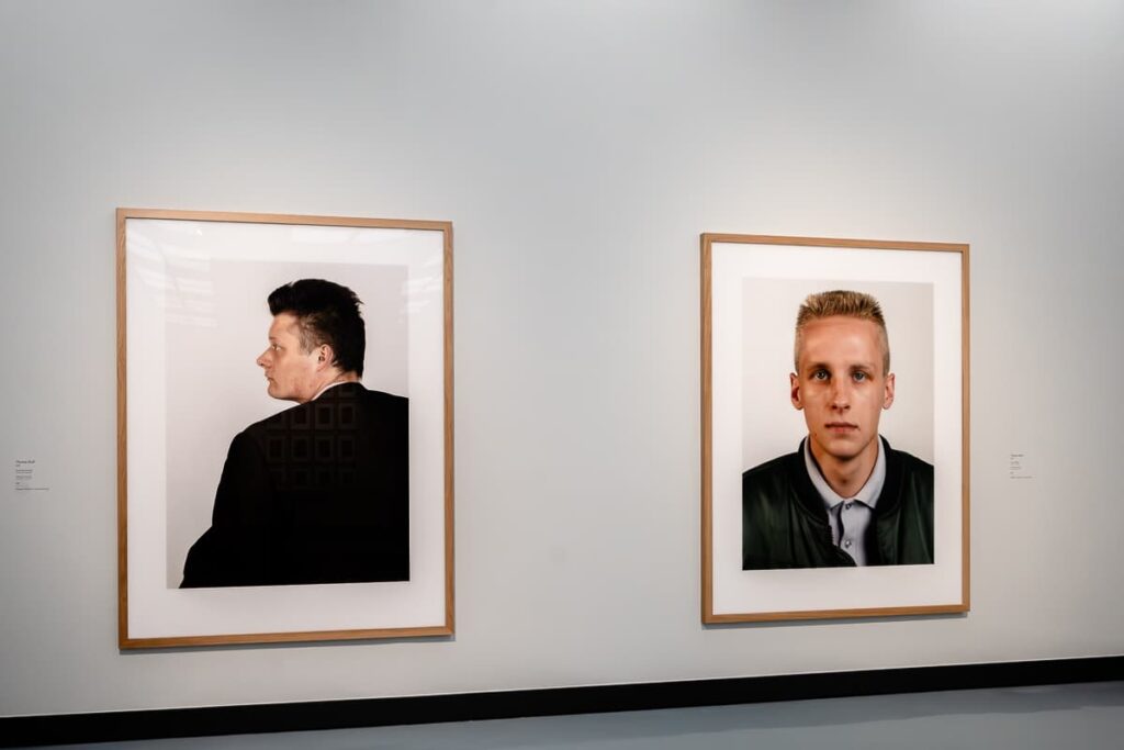 Zwei großformatige Portraits von Thomas Ruff, nicht weiter im Katalog benannt. Rechts mehr wie ein Passfoto, ein Mann mit einem kurzen Bürstenhaarschnitt, Hemd, dünne Jacke. Links: ein älterer Mann, mit dem Rücken zugewandt, nach links schauend, ebenfalls Kurzhaarschnitt. Beides sieht nach 1980er Jahre aus. 