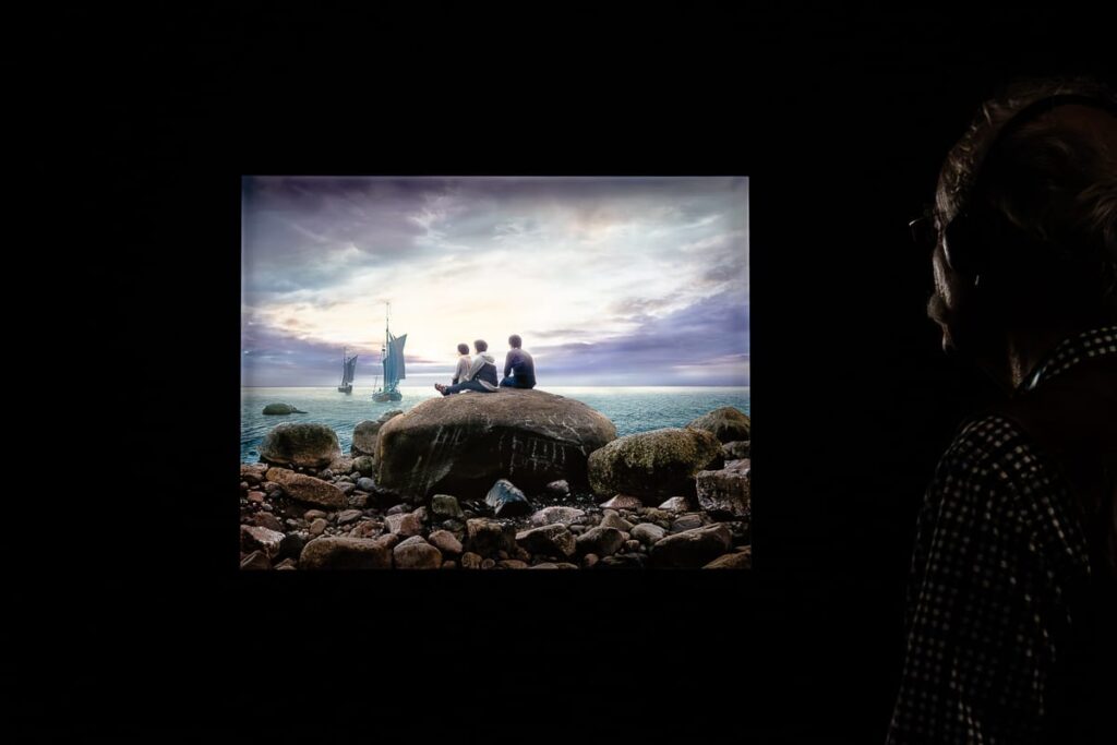 LED-Leuchtkasten von Hiroyuki Masuyama mit "Fotomontage nach Caspar David Friedrich, Mondaufgang am Meer 1822" (2018) in einem dunklen Raum, ein älterer Herr am rechten Rand, der das Bild betrachtet. 