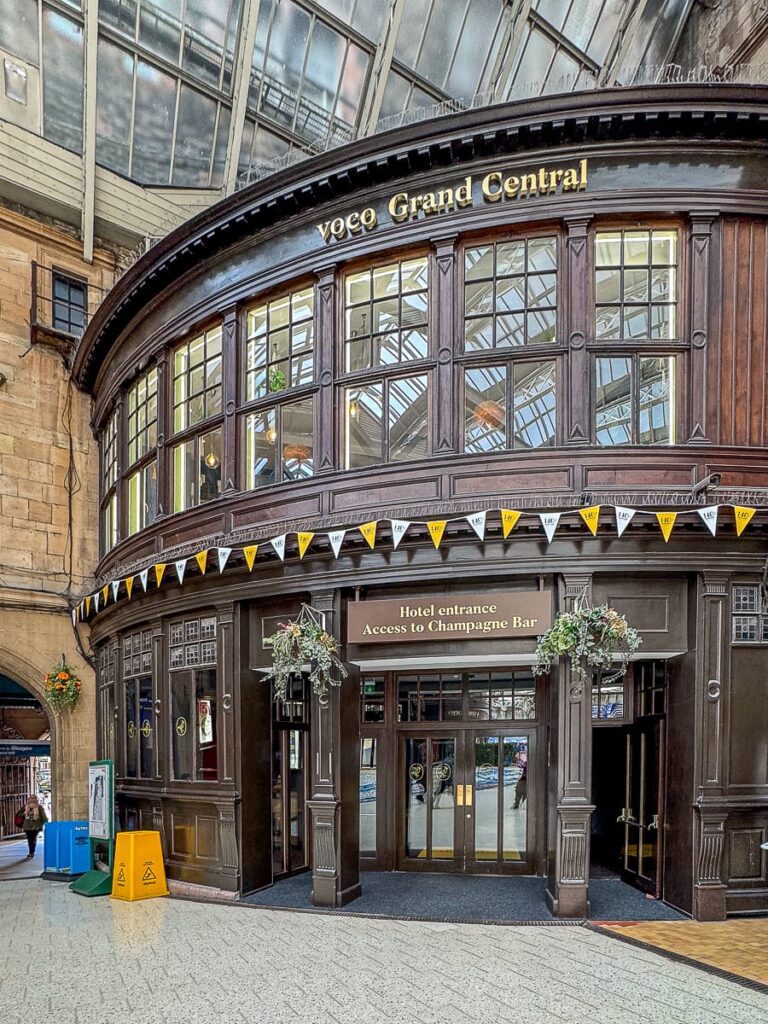 Eingang zum voco Grand Hotel in der Bahnhofshalle von Glasgow Central - halbrunder Holzbau mit kleinen Glasfenstern im ersten Stock.